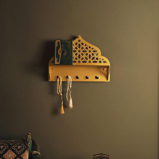Decorative wall shelf with intricate design on a dark wall, next to a green sofa and decorative mirror.