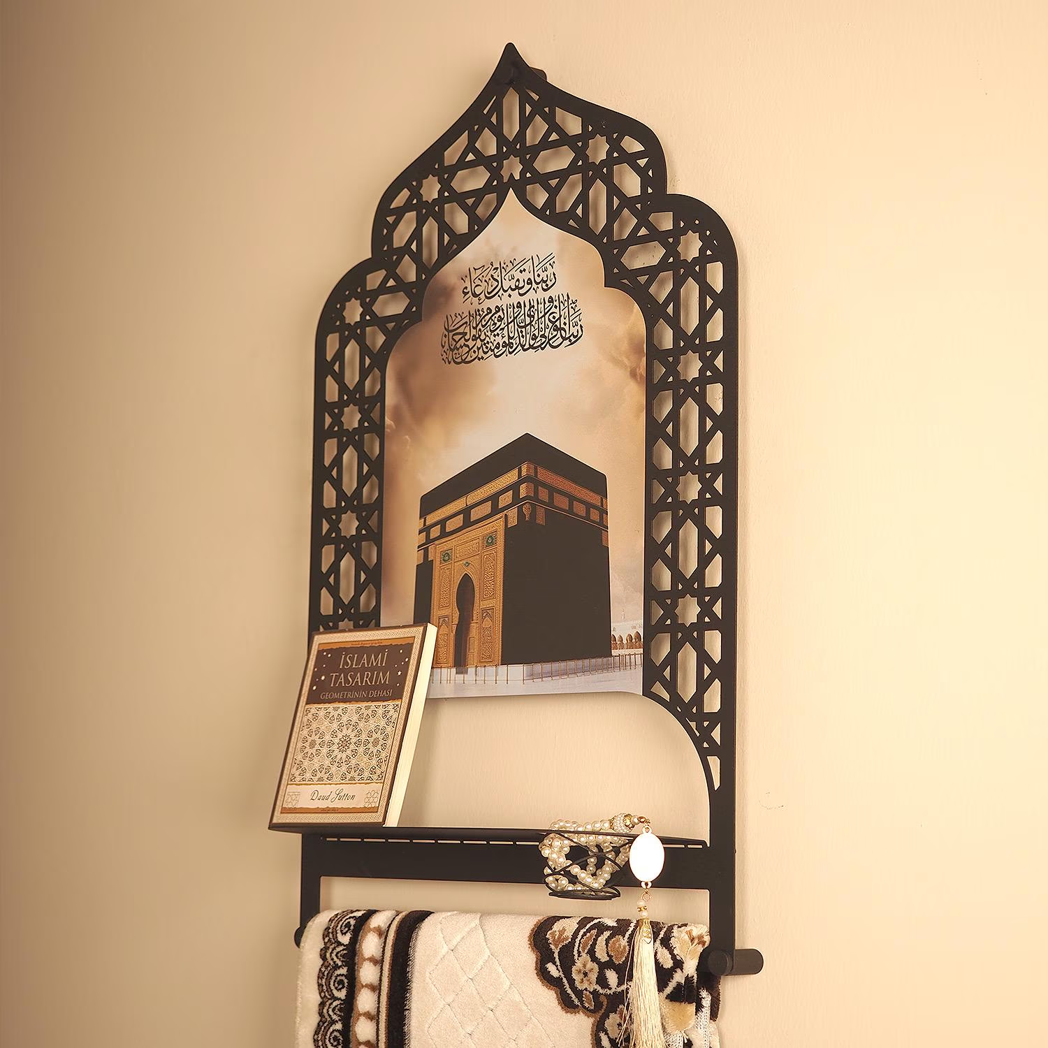Decorative wall mirror with intricate black frame featuring a religious design, placed on a beige wall.