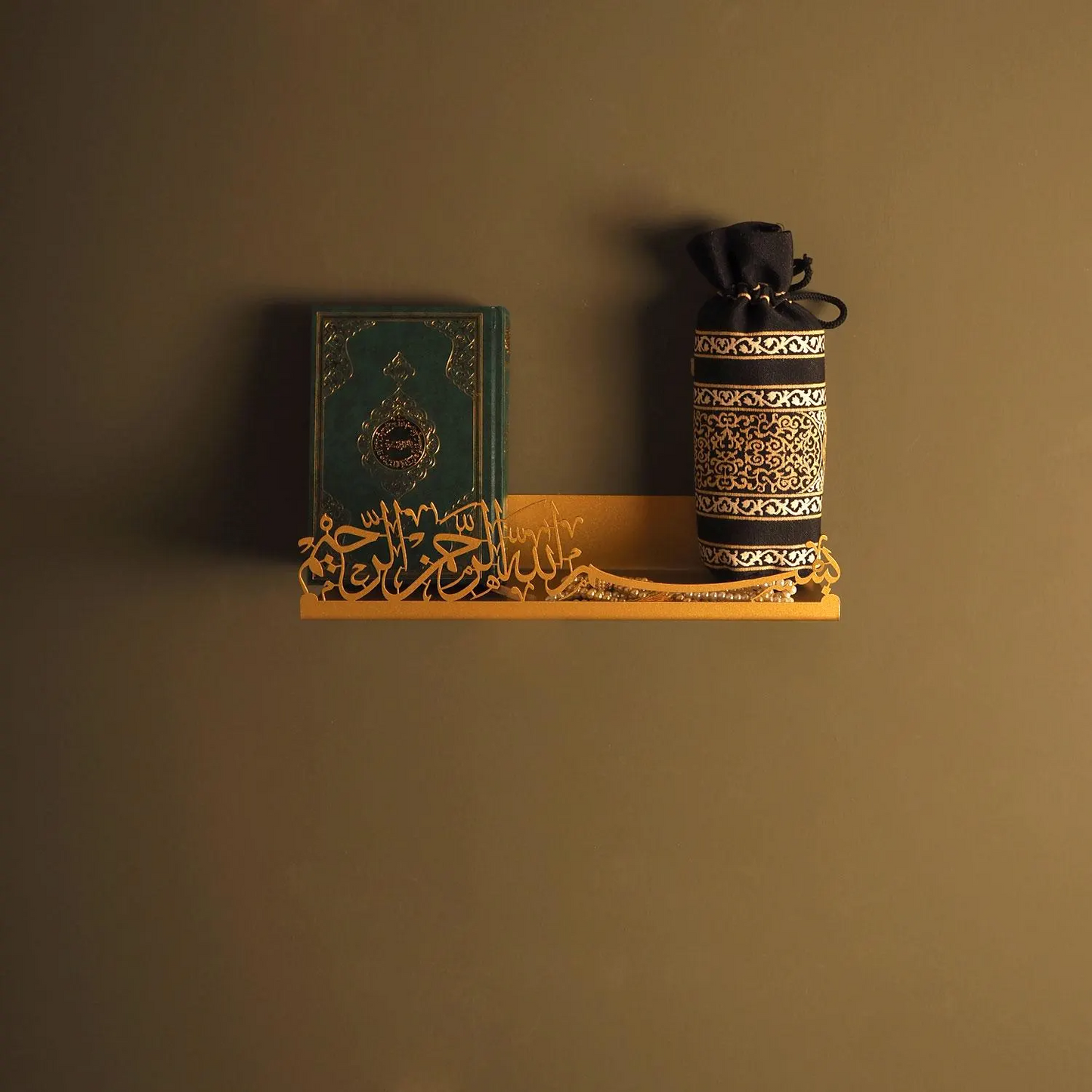 Decorative shelf with a book and a cylindrical container against a brown wall